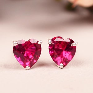 以下が含まれることがあります： 銀にセットされた鮮やかな赤い宝石がついたハート型のイヤリングのペア
