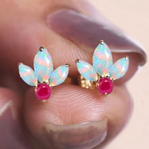 May include: Gold earrings with a cluster of five opal stones and a single ruby stone in the centre.