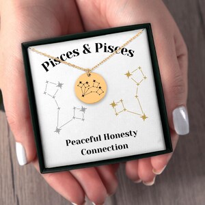 Könnte beinhalten: Goldkette mit einem Anhänger mit dem Sternbild Fische. Die Kette befindet sich in einer schwarzen Schachtel mit den Worten "Pisces & Pisces" und "Peaceful Honesty Connection".