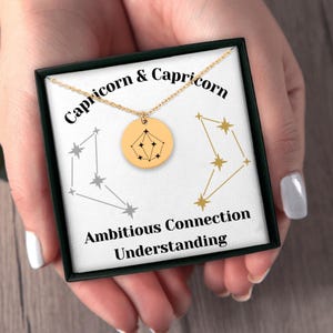 Könnte beinhalten: Eine goldene Halskette mit einem Capricorn-Sternbild-Anhänger in einer schwarzen Schachtel mit dem Text "Capricorn & Capricorn, Ehrgeizige Verbindung Verständnis".