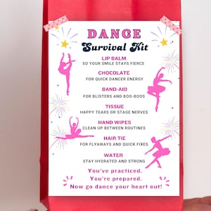 May include: A red gift bag with a white card. The card reads "DANCE Survival Kit" and lists items such as lip balm, chocolate, band-aids, tissue, hand wipes, hair tie, and water, with pink ballerina illustrations.