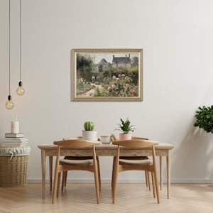 May include: A framed landscape painting depicting a garden scene with a house in the background. The painting has a gold frame and is hanging above a wooden dining table with chairs. Decorative plants and a basket are also in the room.