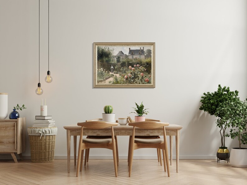 May include: A framed landscape painting depicting a garden scene with a house in the background. The painting has a gold frame and is hanging above a wooden dining table with chairs. Decorative plants and a basket are also in the room.