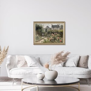 May include: A framed painting depicts a garden scene with a house in the background. The garden features rose bushes with pink blooms, a pathway, and figures. The painting is displayed on a white wall above a gray sofa, enhancing the room's decor.