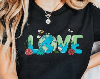 May include: A black t-shirt featuring a graphic of the word "LOVE" in colourful letters. The "O" is replaced with a cartoon image of the Earth with a smiling face. The graphic also includes bees, flowers, and leaves.