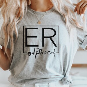 May include: Gray t-shirt with a black graphic design that says "ER Nurse" with a stethoscope and a heartbeat graphic.