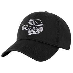 Könnte beinhalten: Eine schwarze Baseballkappe mit einer weißen Stickerei eines kleinen Pritschenwagens auf der Vorderseite. Die Kappe verfügt über einen gebogenen Schirm, eine strukturierte Krone mit einem Knopf oben und genähte Ösen zur Belüftung.