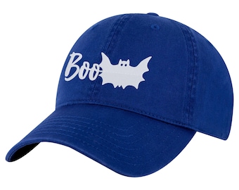 Op de afbeelding: Een koningsblauwe baseballpet met een witte afbeelding van een vleermuis en het woord "Boo" in cursief schrift op het voorpaneel. De pet heeft een gebogen klep, een gestructureerde kroon en een knoopje bovenop het midden van de koepel.
