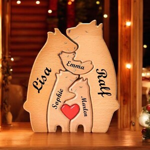 Könnte beinhalten: Holzpuzzle einer Bärenfamilie mit den Namen Lisa, Ralf, Emma, Sophie und Marlene. Die Bären sind in einer Umarmung mit einem roten Herzen in der Mitte angeordnet.