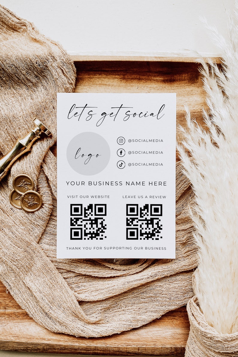 May include: A white card with the text "let's get social" and a logo placeholder. The card also includes social media handles for Instagram, Facebook, and TikTok, as well as QR codes for visiting the website and leaving a review. The text "YOUR BUSINESS NAME HERE" is also included.