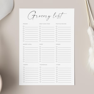 Może przedstawiać: Biały notatnik z listą zakupów z napisem "Grocery list" w eleganckiej czcionce. Notatnik podzielony jest na sekcje dla mrożonek, mięsa i owoców morza, owoców i warzyw, piekarni i delikatesów, nabiału, napojów, spiżarni, gospodarstwa domowego i innych.
