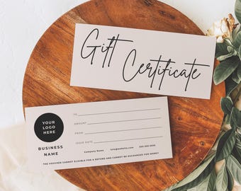 May include: Two gift certificates on a wooden surface. The top certificate reads "Gift Certificate" in elegant script. The bottom certificate has space for a logo, business name, and recipient information. The background is a light beige color.