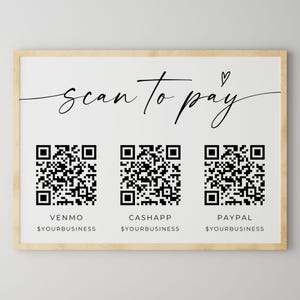 May include: White sign with a black frame and the text "Scan to pay" with a heart symbol. There are three QR codes with the names Venmo, Cashapp, and Paypal underneath each code. Each name has the text "$yourbusiness" underneath.