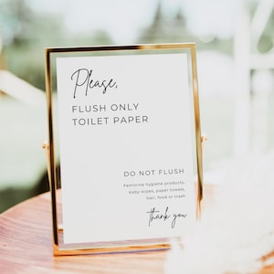 May include: A gold-framed sign with the text "Please, FLUSH ONLY TOILET PAPER" and "DO NOT FLUSH" followed by a list of items. The sign is on a wooden surface. The words "Thank you" are at the bottom.