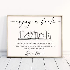 Peut inclure: Une affiche encadrée avec l'inscription "enjoy a book" en écriture élégante. En dessous, une étagère avec des livres illustrés et une plante succulente. Le texte encourage le partage de livres : "Les meilleurs livres sont partagés. N'hésitez pas à prendre ou à laisser un livre pour que d'autres en profitent." Lieu : Miami, Floride.
