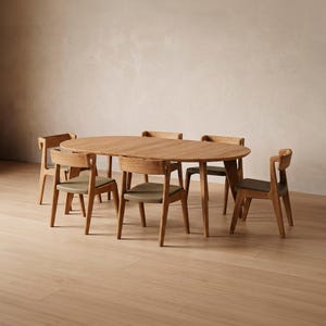 Può includere: Un tavolo da pranzo ovale in legno con sei sedie abbinate. Le sedie hanno cuscini di seduta verde chiaro e telai in legno. Il tavolo e le sedie sono su un pavimento in legno chiaro, creando un set da pranzo moderno e coeso.