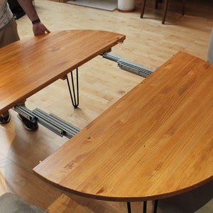 Extendable round wooden table with metal legs.