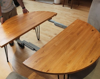 Tavolo rotondo allungabile in legno con gambe in metallo.