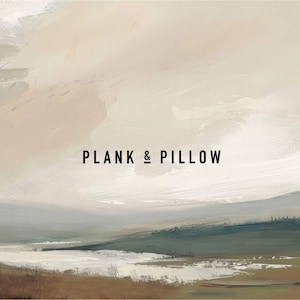 May include: A painting of a landscape with a light brown, white, and gray color scheme. The painting depicts a body of water in the foreground with hills in the background. The text 'PLANK & PILLOW' is centered in the middle of the image.