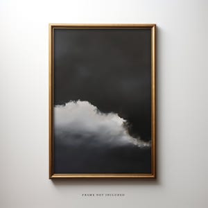 May include: A framed art print featuring a dramatic cloudscape. The artwork showcases a large, fluffy white cloud against a dark gray background. The frame is a thin, gold color. The text "FRAME NOT INCLUDED" is at the bottom.