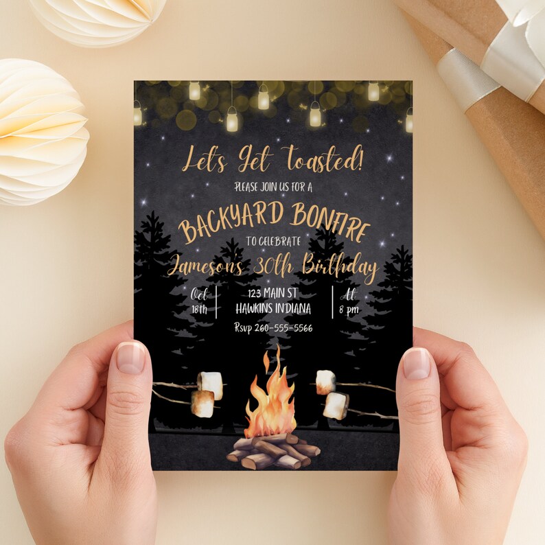 May include: A black and gold invitation for a backyard bonfire to celebrate a 30th birthday. The invitation features a campfire with marshmallows roasting on sticks, a starry night sky, and string lights. The text reads "Let's get toasted! Please join us for a backyard bonfire to celebrate Jameson's 30th birthday. Oct 18th, 123 Main St, Hawkins Indiana, At 8 pm, Rsvp 260-555-5566."