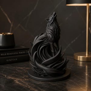 Puede incluir: Una escultura de color negro mate de un lobo aullando al cielo, colocada sobre una base circular. El lobo está rodeado de elementos estilizados, fluidos y curvos que recuerdan al viento o al pelaje, creando un aspecto dinámico y texturizado.
