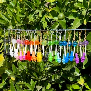 May include: A set of 20 pairs of earrings featuring colorful lollipop charms and silicone earplugs in various colors, including black, white, red, orange, yellow, green, blue, purple, and pink.