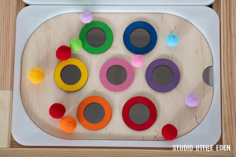 May include: A wooden toy with colorful rings and balls. The rings are different colors, including green, blue, pink, purple, yellow, and orange. The balls are also different colors, including red, blue, green, pink, and white. The toy is designed for children to play with and learn about colors and shapes.