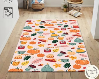 Puede incluir: Una alfombra rectangular con fondo rosa claro presenta un patrón repetido de calabazas, hojas, tazas de café y porciones de pastel. Las palabras "happy fall" y "JAM" también están incluidas. La alfombra está diseñada para uso en interiores.
