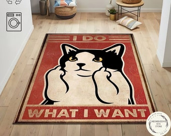 May include: A red and white rug featuring a black and white cat illustration. The cat is giving the middle finger with both hands. The text on the rug reads "I DO WHAT I WANT".