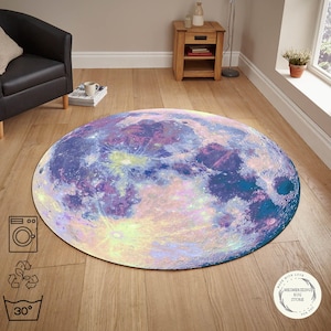 May include: A round rug with a detailed, colorful design resembling the moon's surface. The rug features shades of blue, purple, and yellow, creating a celestial aesthetic. The rug is placed on a wooden floor.