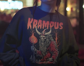 May include: A person wearing a dark gray sweatshirt with the word "KRAMPUS" in orange lettering. The sweatshirt features a graphic of a horned creature holding a flaming orb. The background is a city street at night.