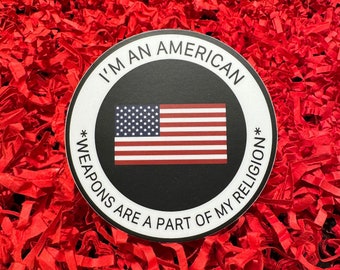 May include: A black and white sticker with the text "I'm an American *Weapons are a part of my religion*" and a red, white, and blue American flag.