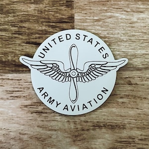 May include: White sticker with black text and a black propeller design. The text reads "United States Army Aviation".