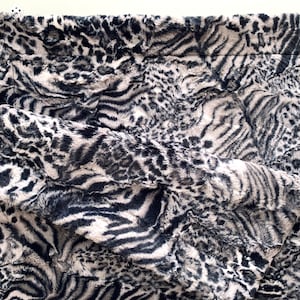 May include: A black and white faux fur throw blanket with a zebra and leopard print pattern.