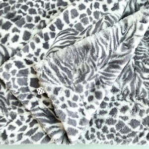 May include: A soft, plush blanket with a gray and white zebra and leopard print pattern.