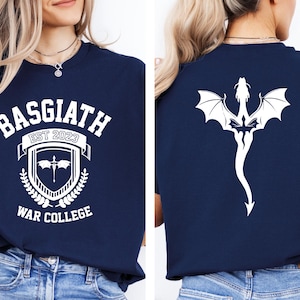May include: A navy blue t-shirt with a white graphic design on the front. The design features a crest with the text "Basgiath Est 2023 War College". The back of the shirt features a white dragon design.