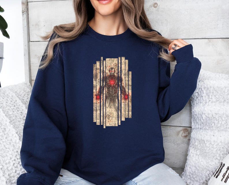 May include: Navy blue sweatshirt featuring a graphic of Iron Man. The design shows a detailed illustration of the character's armor and internal components, set against a backdrop of vertical, aged paper-like panels.