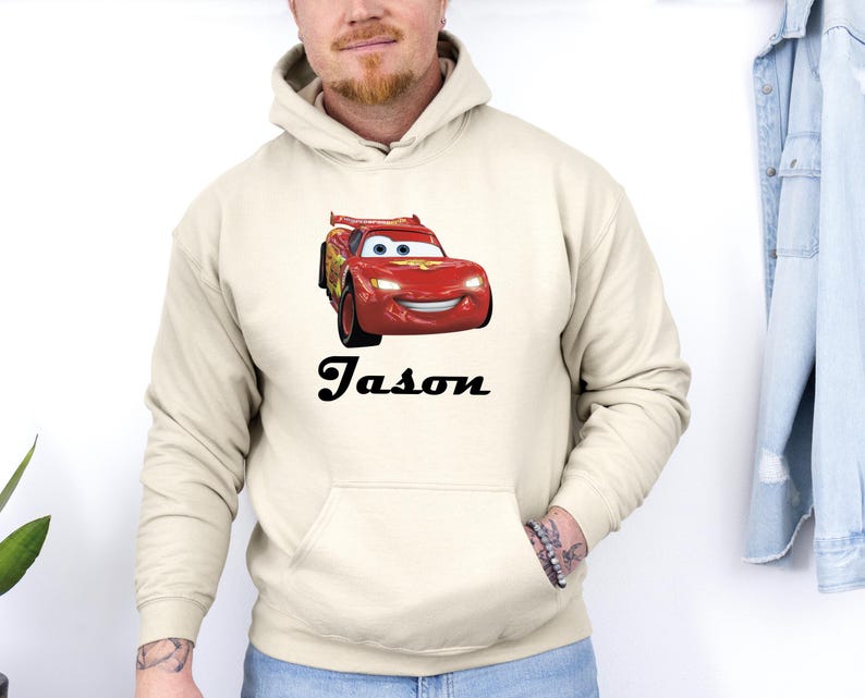 Puede incluir: Sudadera con capucha color crema con un gr&aacute;fico de coche de carreras rojo. El nombre "Jason" est&aacute; impreso en negro debajo. La sudadera tiene un bolsillo delantero y una capucha con cord&oacute;n.