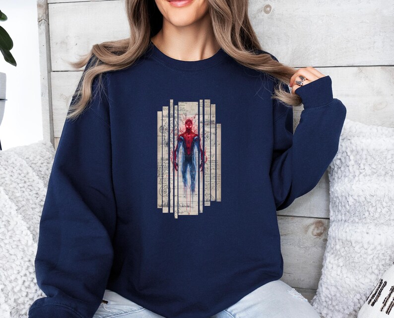Op de afbeelding: Marineblauwe sweatshirt met een Spiderman-afbeelding. De afbeelding toont Spiderman in een rood-blauw pak, tegen een achtergrond van verticale lijnen en muzieknoten. De sweatshirt heeft lange mouwen en een ronde hals.