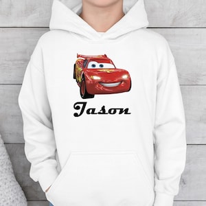 Puede incluir: Sudadera con capucha blanca con un coche de carreras rojo de dibujos animados con una cara sonriente. El nombre "Jason" est&aacute; impreso en negro debajo. La sudadera tiene un bolsillo delantero y una capucha con cord&oacute;n.