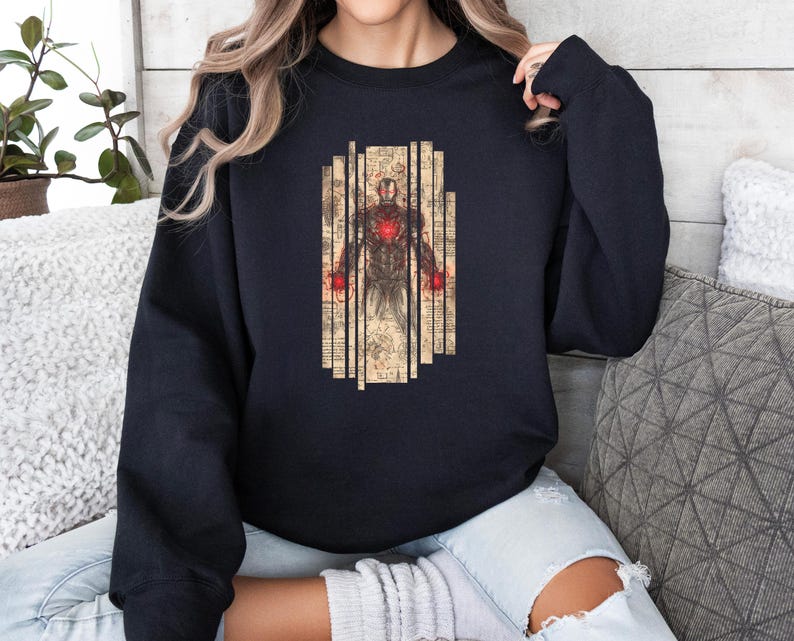 May include: A black sweatshirt featuring a graphic of a figure with a red heart and red hands, set against a backdrop of vertical beige panels with vintage-style text. The design is centered on the front of the sweatshirt.