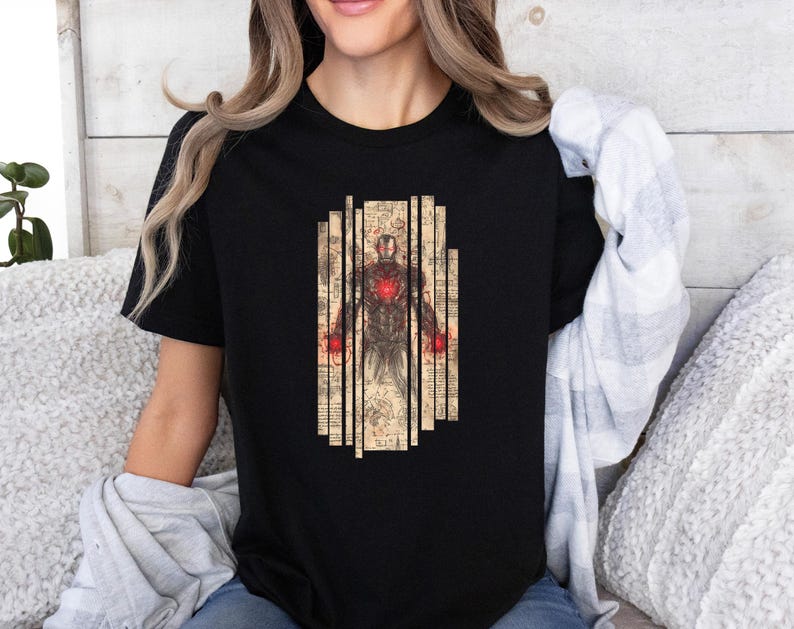 May include: Black t-shirt featuring a detailed illustration of Iron Man. The design includes a central figure of Iron Man with a glowing red chest and hands, set against a backdrop of vertical, aged paper-like panels. The artwork has a vintage, sketched aesthetic.