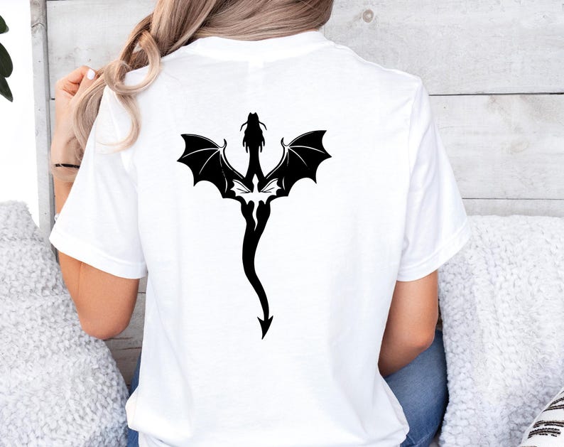 May include: White t-shirt with a black silhouette of a dragon with wings spread out on the back.