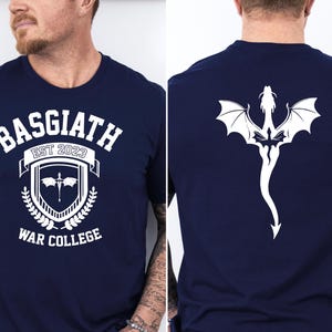 May include: A navy blue t-shirt with a white graphic design on the front. The graphic features a shield with a sword and the text "Basgiath Est 2023 War College". The back of the shirt features a white dragon design.