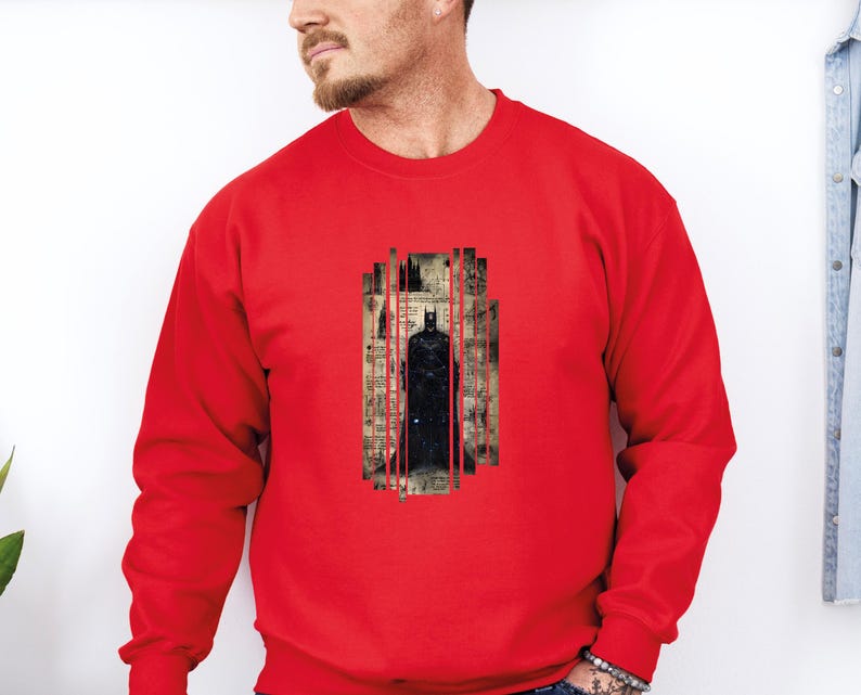 Puede incluir: Una sudadera roja con un gr&aacute;fico de Batman. El gr&aacute;fico muestra a Batman frente a un paisaje urbano con l&iacute;neas verticales rojas. El dise&ntilde;o est&aacute; impreso sobre un fondo de estilo vintage.