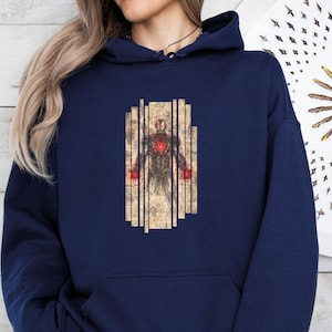 May include: Navy blue hoodie featuring a graphic of a figure with a red heart and hands, set against a backdrop of vertical, aged paper-like panels. The design has a vintage, comic book style.