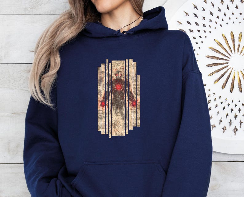 May include: Navy blue hoodie featuring a graphic of a figure with a red heart and hands, set against a backdrop of vertical, aged paper-like panels. The design has a vintage, comic book style.