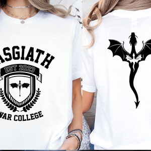 May include: White t-shirt with a black graphic design featuring the text "BASGIATH EST 2023 WAR COLLEGE" and a shield with a dragon inside. The back of the shirt features a black dragon design.