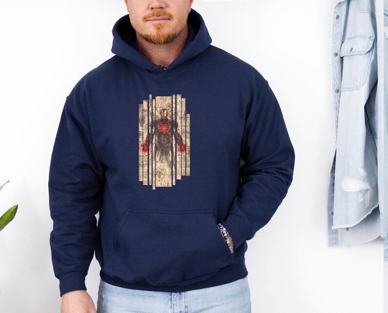 May include: Navy blue hooded sweatshirt featuring a graphic of a superhero. The graphic is a detailed illustration of a figure with a red chest and red hands, set against a backdrop of vertical lines. The sweatshirt has a front pocket.